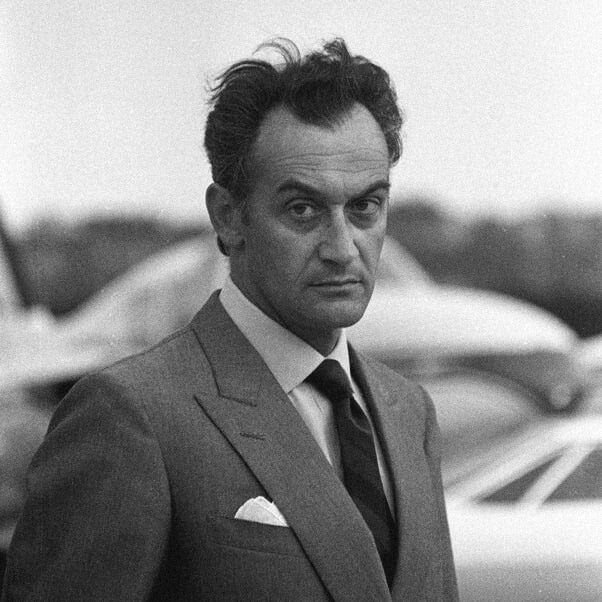 Discover the elegance of a 1950s car designer in a suit, shaping a clay model. (77 characters)